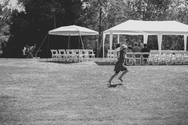 Little girl running across grass before the wedding ceremony.