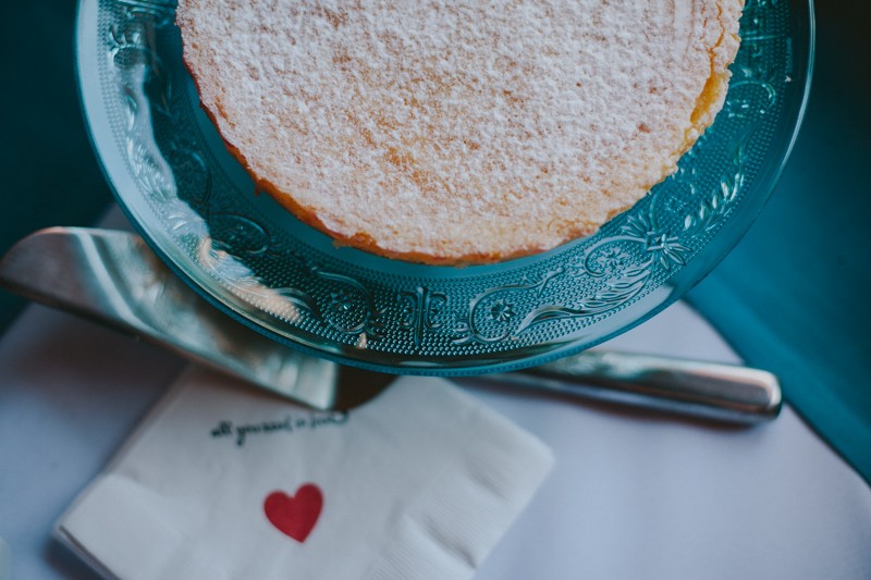 Lemon tart dusted with powdered sugar topping, on a vintage blue dessert plate. 