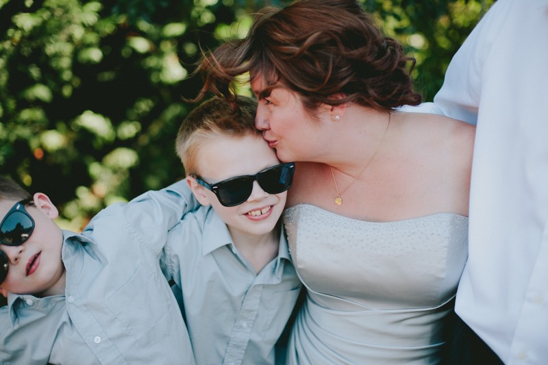 Bride whimsically kissing her son on the forehead. 