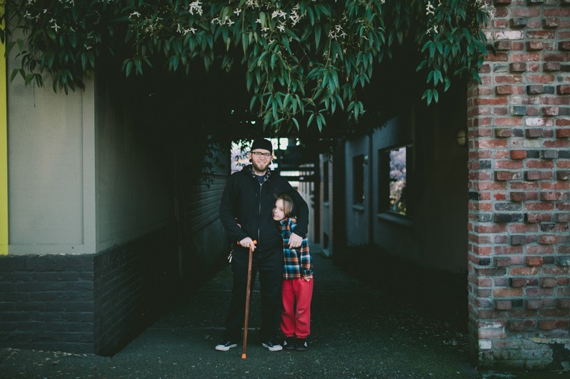 Dad and son hug under springtime greenery.