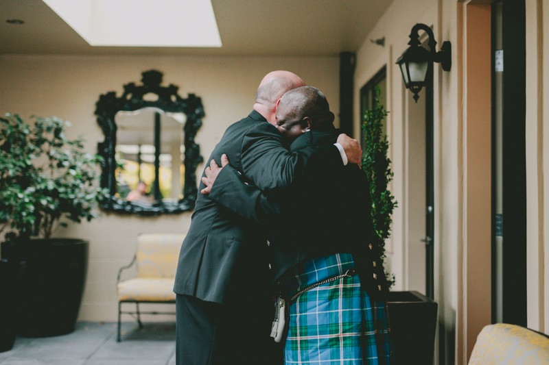 Two grooms hug during their first look at Hotel Ballard. 