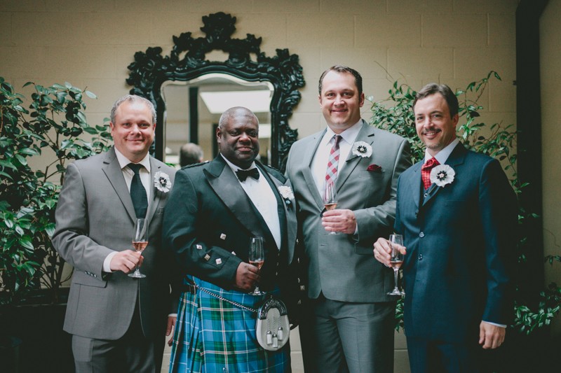 Groom in a kilt and peak lapel jacket stands with his groomsmen at Hotel Ballard. 