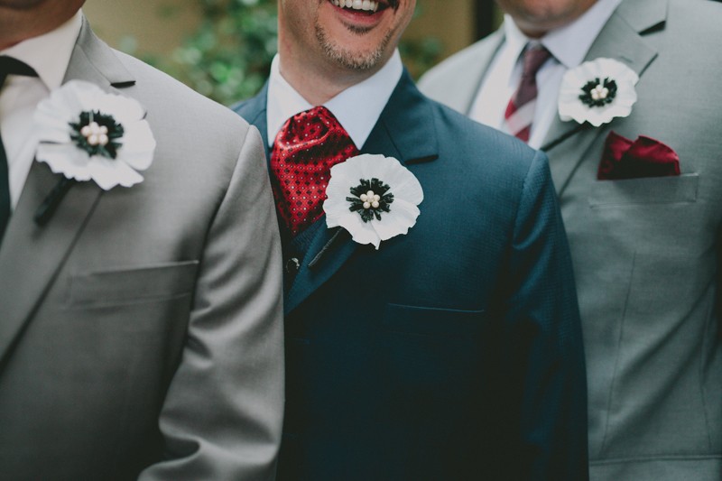 Groomsmen in grey and blue suits with red details, and handmade paper flower boutonnieres. 