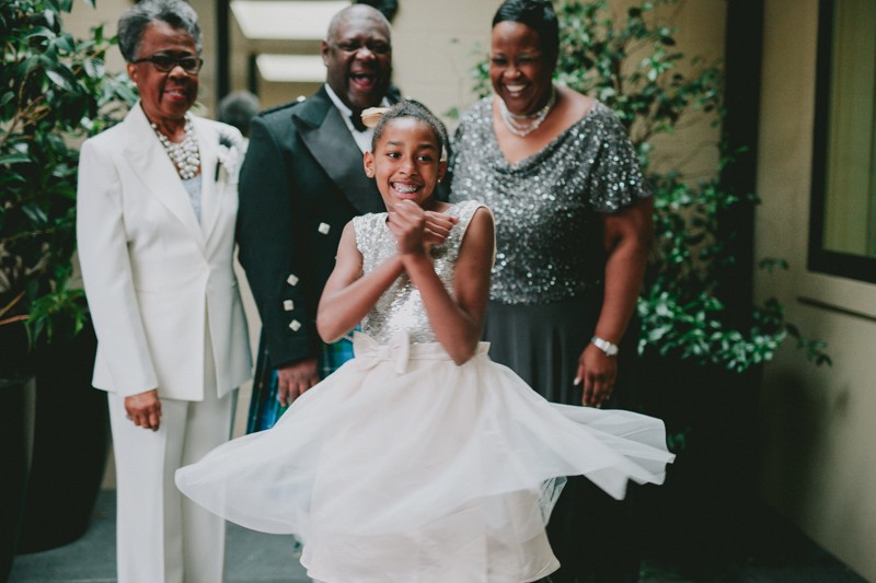 Groom laughs as his niece twirls in a sparkly white dress. 