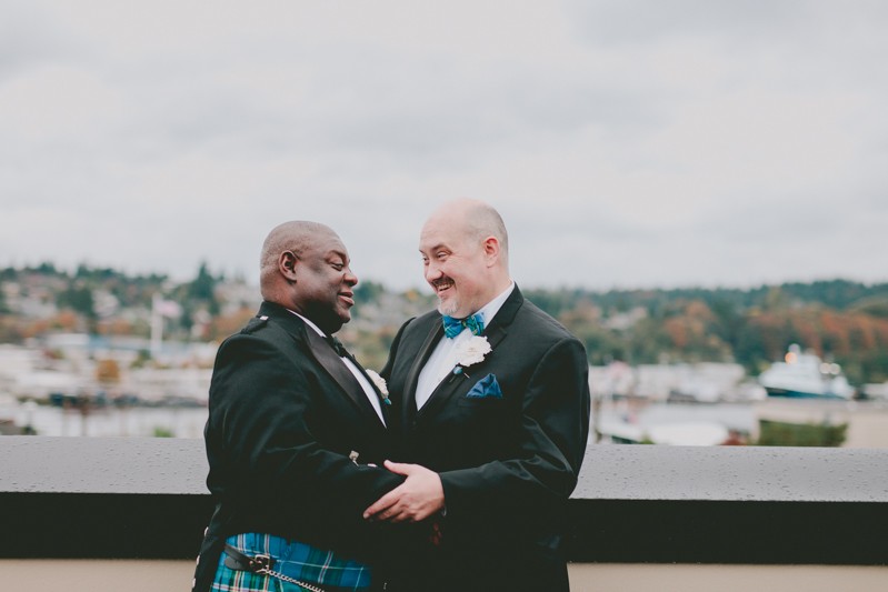 Grooms laugh together on the rooftop of Hotel Ballard. 