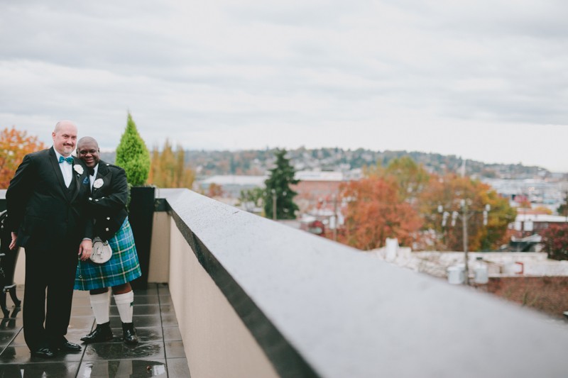 Two classy grooms in bow ties overlook Seattle, at the Rooftop Pavilion at Ballard Hotel. 