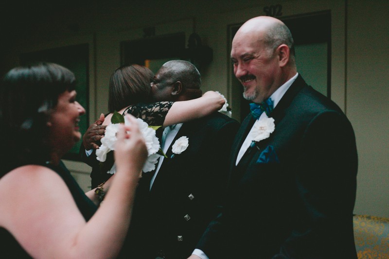 Same sex couple hugs bridesmaids after wedding ceremony. 