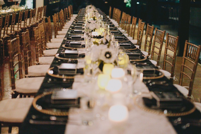 Candle light rooftop wedding reception, with long tables and gold chiavari chairs. 