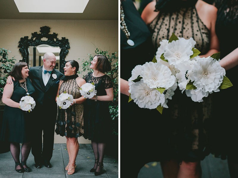 Groom with his groomsmaids, wearing knee-length dresses and holding handmade paper flower bouquets. 