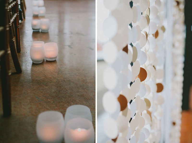 Candle light ceremony with tea lights lining the aisle, and a paper garland backdrop at the altar. 