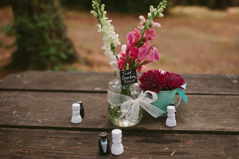 Simple wildflower centerpiece with pink and white flowers, and a small chalkboard sign. 