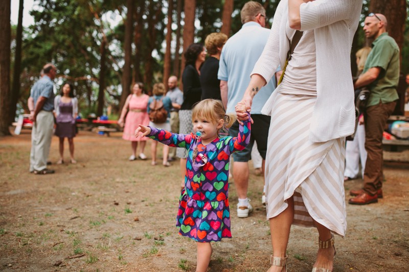 Toddler wedding guest in pigtails, with a vibrant heart-patterned dress. 