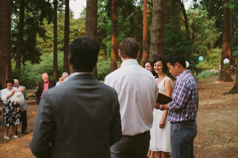 Bride looks at groom during woodsy wedding ceremony. 