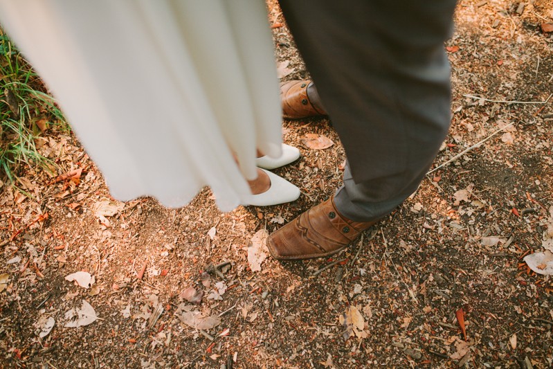 Bride wearing white high heels and groom in brown leather shoes. 