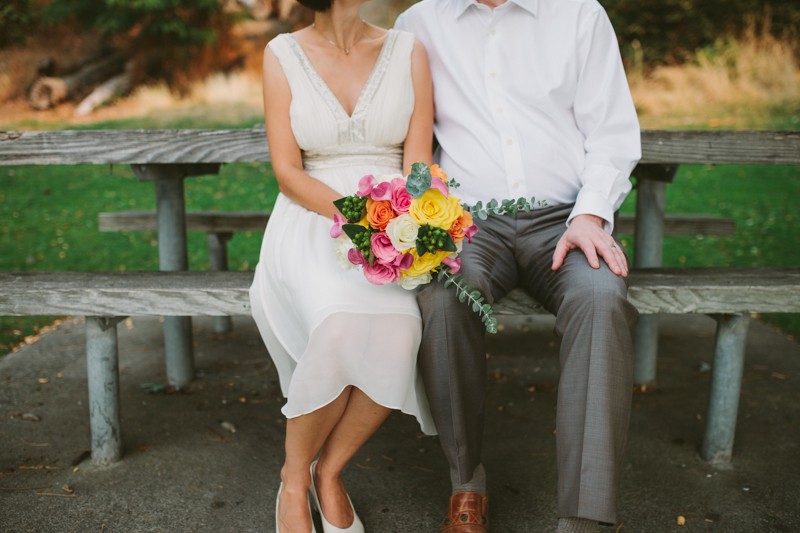 Seattle bride wearing a beaded v-neck wedding dress, holding a cheery pink and yellow bouquet. 