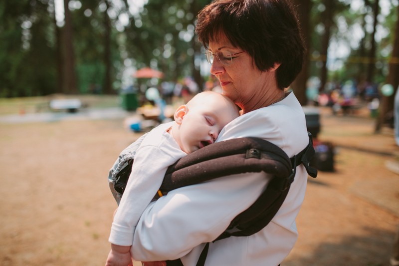 Grandmother holding sleeping baby at a small park wedding in Seattle. 