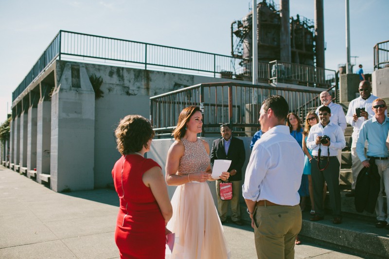 Non-traditional bride in a beaded two-piece dress reads vows to groom. 