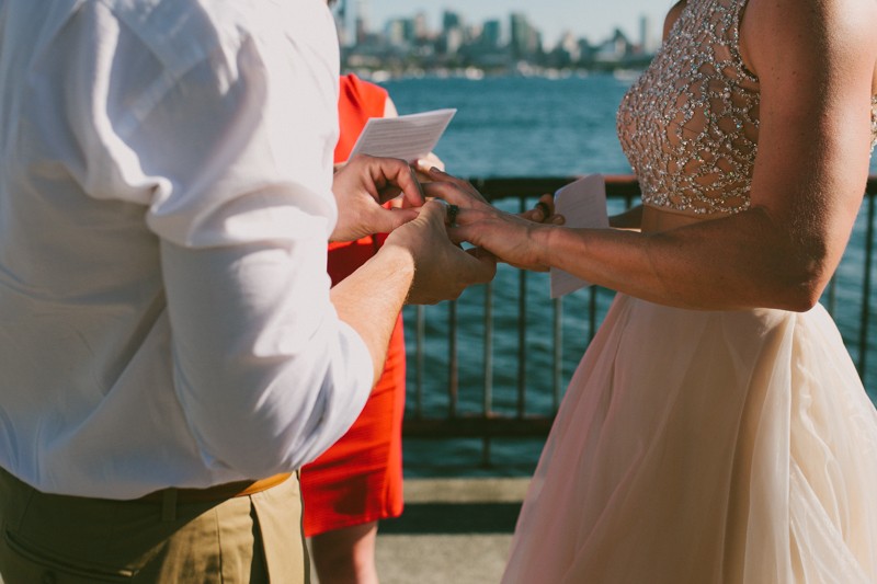 Groom placing ring on bride's finger. 