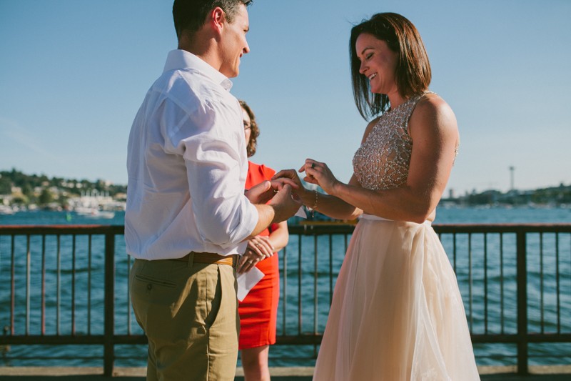 Bride placing ring on groom's finger. 