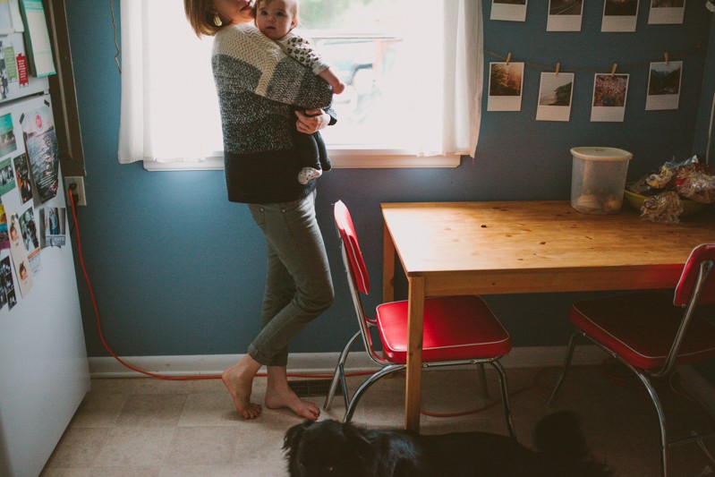 Cute mom and baby in a modern, colorful kitchen with red chairs. 