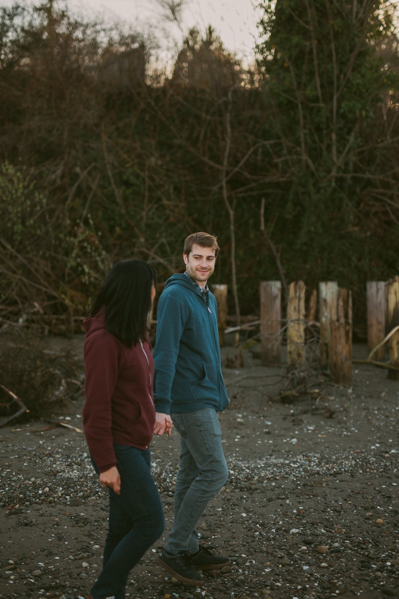 Relaxed beachfront portrait session, with young couple wearing colorful sweatshirts, in Kitsap County, WA. 