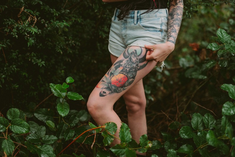 Howling wolf tattoo on upper thigh, at a woodsy portrait session. 