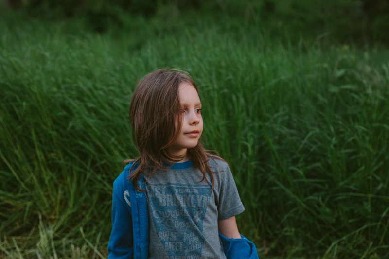 Untraditional portraits on Bainbridge Island, WA, with boy standing in long grass at dusk.