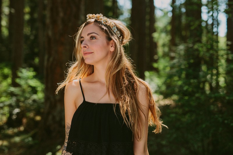 Model with long hair wearing a gold flower crown, in a woodsy state park in the PNW. 