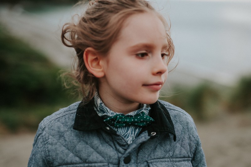 Little boy wearing a patterned, collared shirt with a green polka dot bow tie. 
