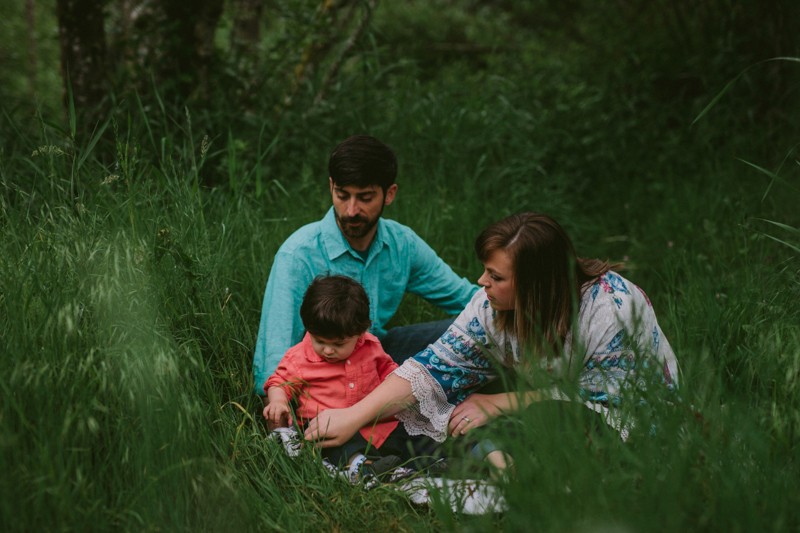 Family photography in Silverdale, WA, with little boy picking grass. 