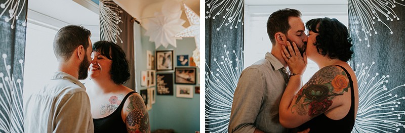 Sweet in home couples portraits, with tattooed couple kissing in front of starburst curtains. 