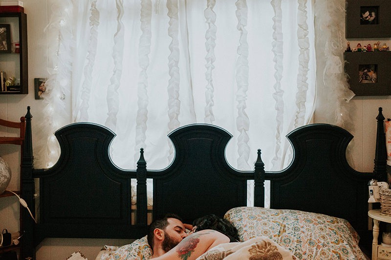 Alternative couples engagement session, cuddling in bed at home. 