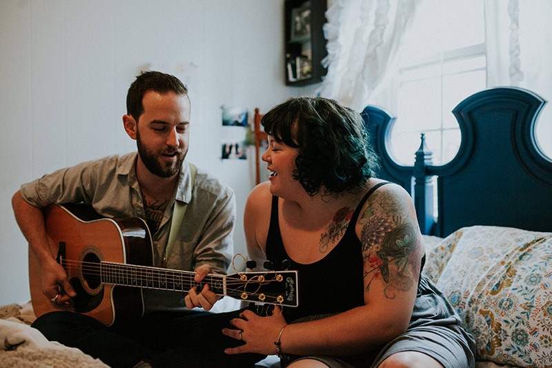Unique portrait session with quirky couple at home, playing guitar together. 