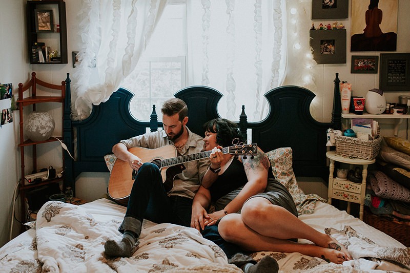 in home portraits of a musician and his wife, cuddling on their bed. 