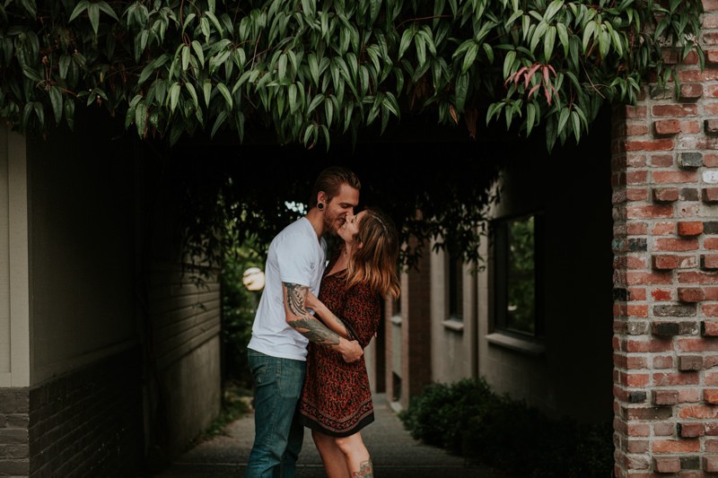 Couple in love kissing under greenery in downtown Winslow, on Bainbridge Island, WA. 