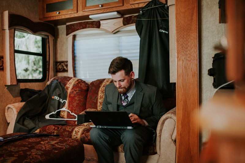 Groom in a suit and vest, preparing music for wedding reception and ceremony. 