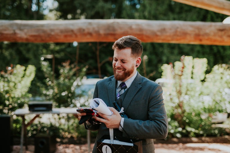 Groom laughing at bride's thoughtful gift to him, with cute socks for cold feet.