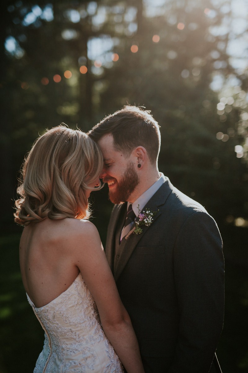 Sweet bride and groom, with groom in a grey suit with a floral boutonniere. 