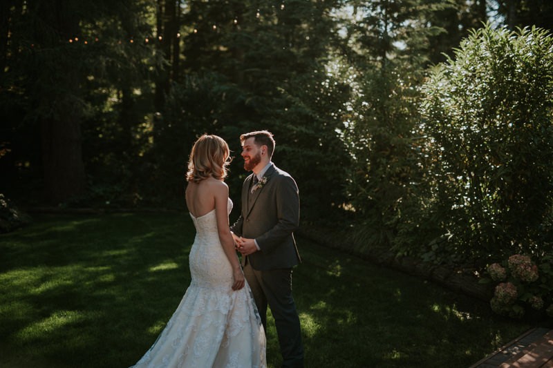 Garden bride and groom first look, with bride in a strapless trumpet dress and groom in a grey suit. 