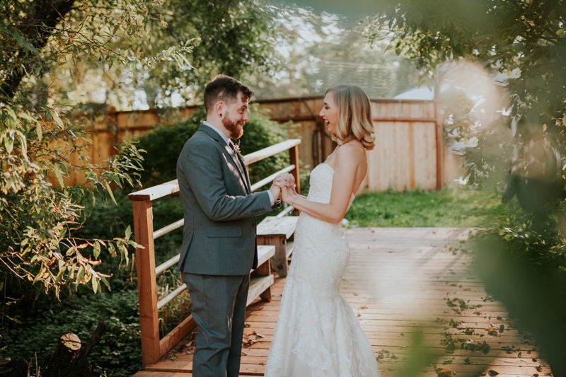 Bride and groom standing on the dock of a pond at Black Diamond Gardens. 