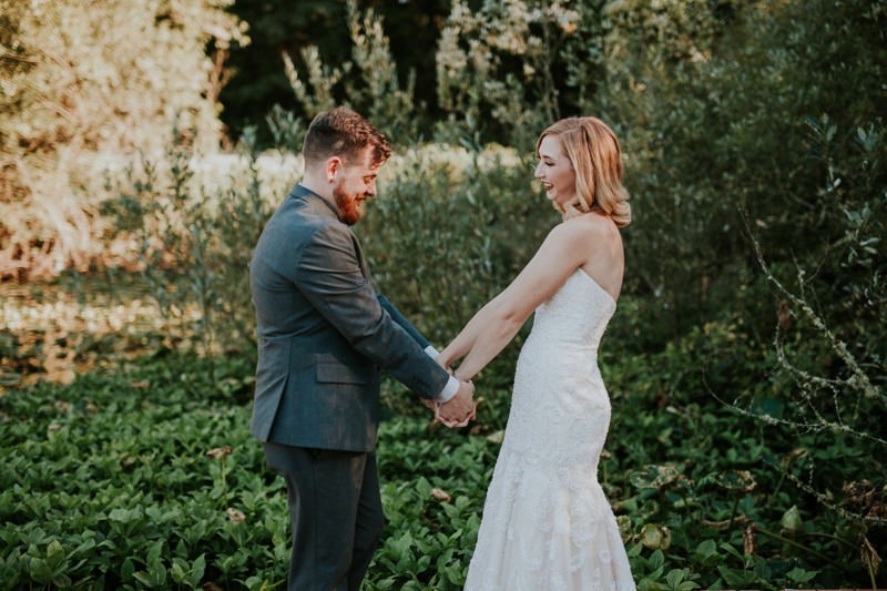 Sweet bride and groom holding hands near a pond full of lily pads, at Black Diamond Gardens. 