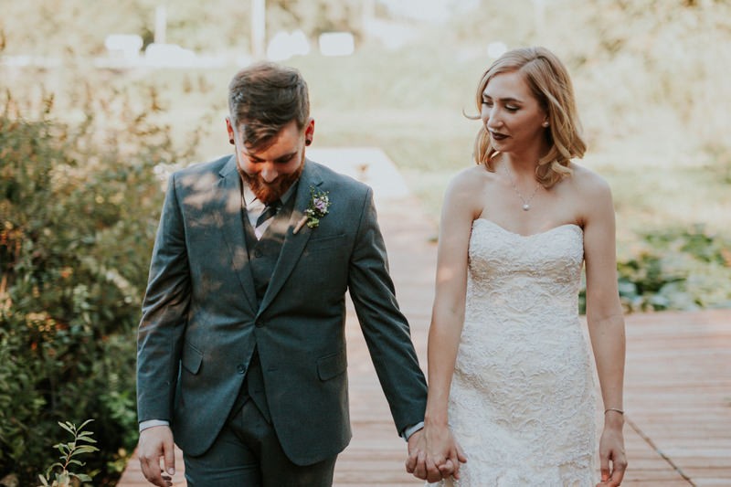 Bride and groom hold hands on a dock at Black Diamond Gardens. 