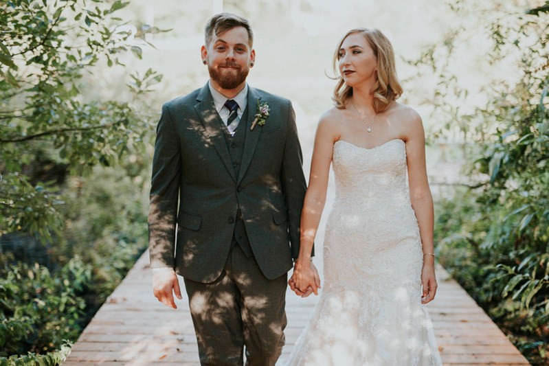 Rad modern bride and groom, with bride in a strapless beaded dress and groom wearing a grey suit and vest.