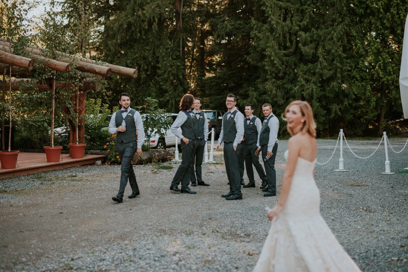 Groomsmen gathered as bride walks by, at Black Diamond Gardens. 