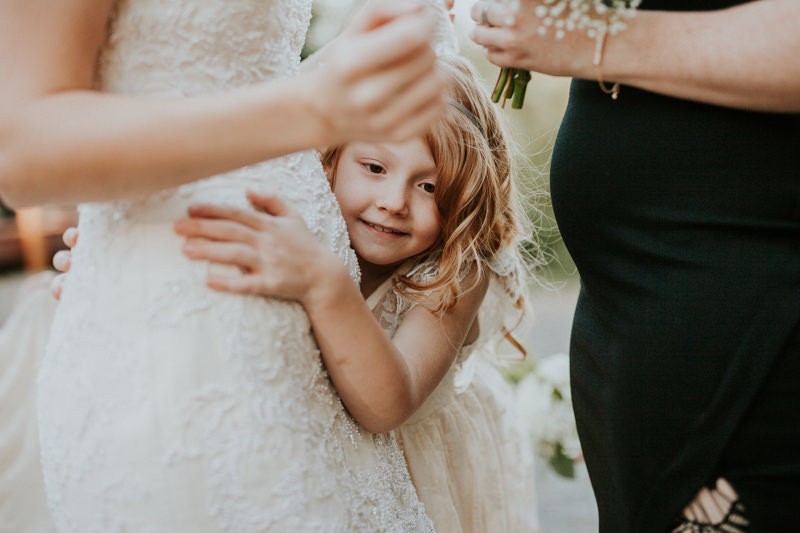 Flower girl hugging the bride. 