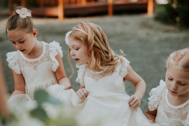 Sweet garden flower girls wearing empire waist lace dresses with cap sleeves and illusion necklines. 