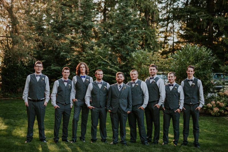 Modern groom and groomsmen, wearing grey vests and purple ties and bow ties. 