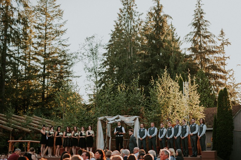 Outdoor wedding ceremony at Black Diamond Gardens, with rustic wooden altar arch. 