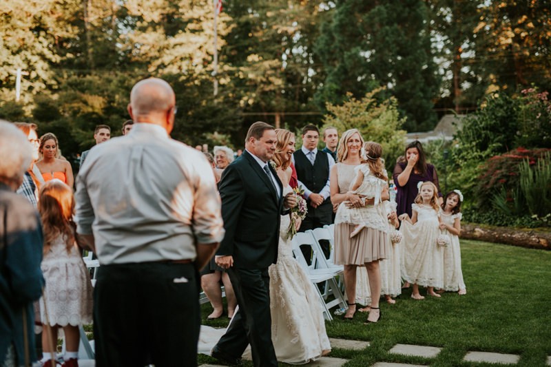 Outdoor wedding at Black Diamond Gardens, with bride's father walking her down the aisle. 