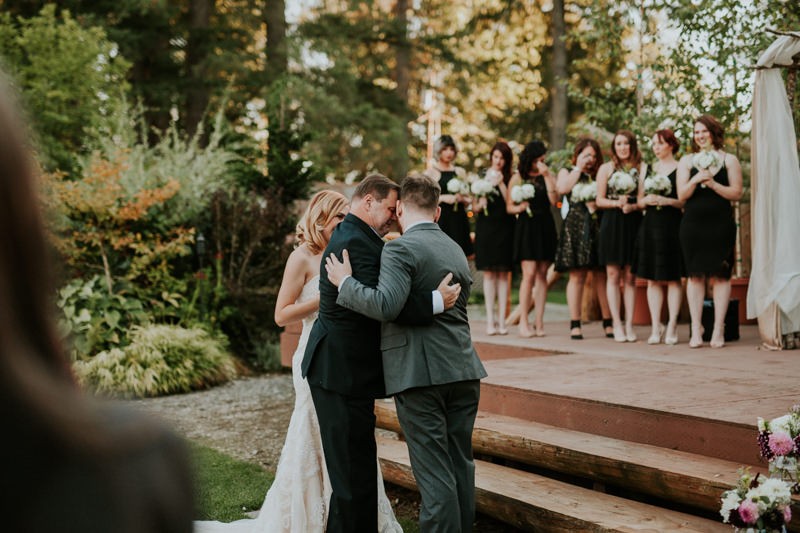 Bride's father hugs the groom as he gives his daughter away at the altar. 